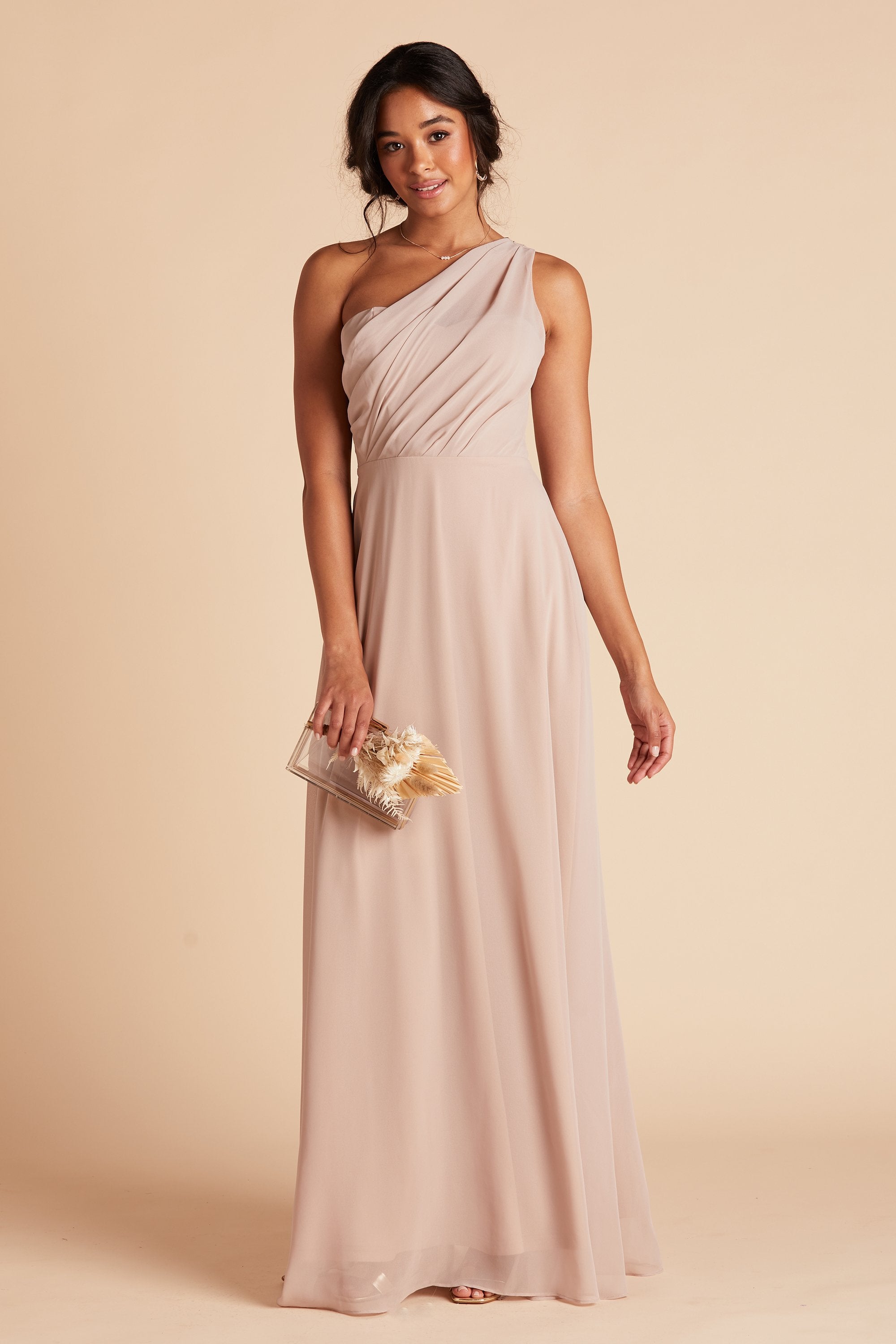 Front view of the Kira Dress in taupe chiffon without the optional slit shows a model holding the Clear Clutch with Clear Beads purse at their side.