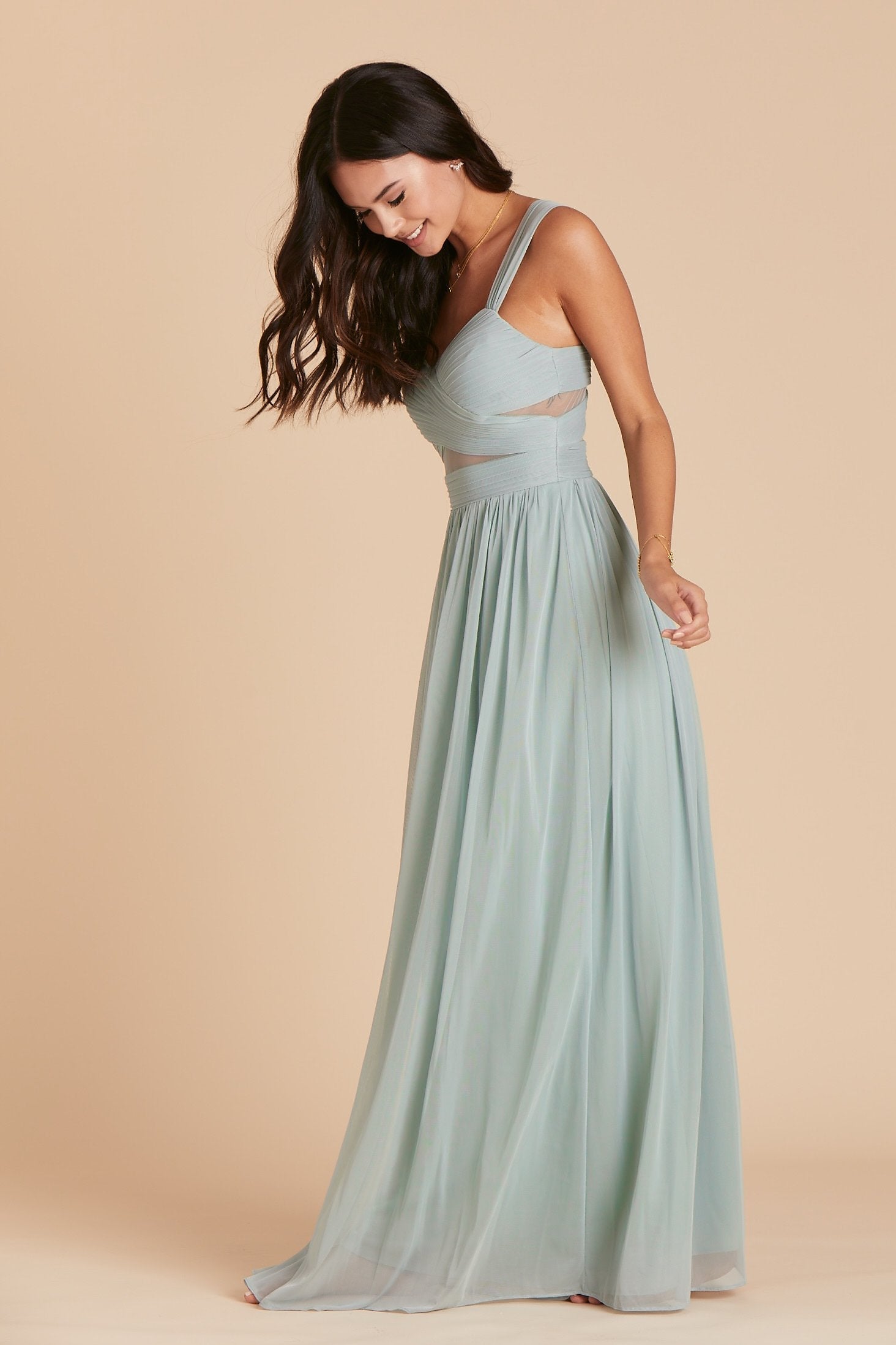 Side view of the floor-length Elsye Bridesmaid Dress in sage mesh features a fitted bust and waist with a flowing skirt that moves with the model.