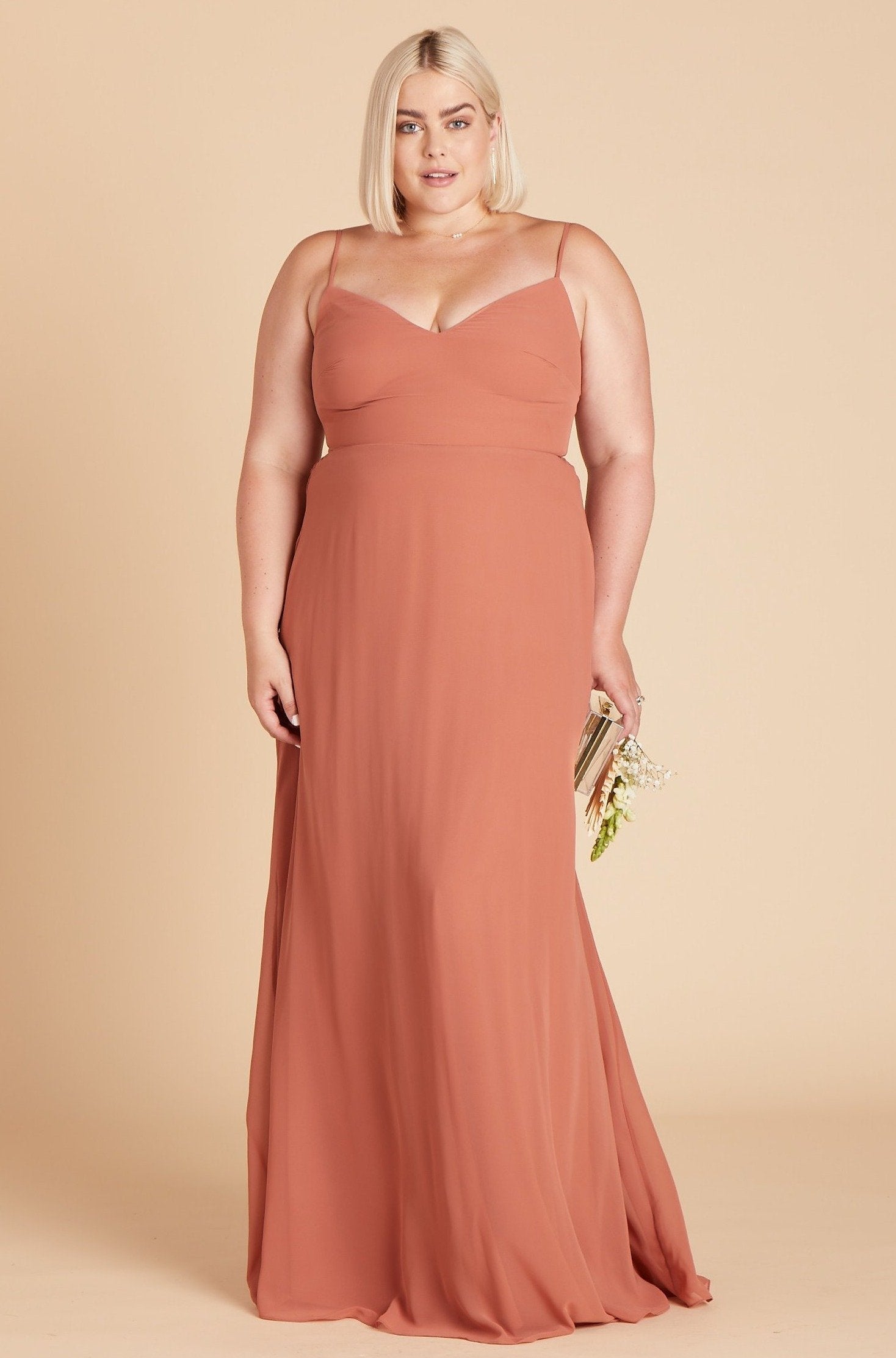 Front view of the floor-length Devin Convertible Plus Size Bridesmaid Dress in terracotta chiffon worn by a curvy model with a light skin tone.