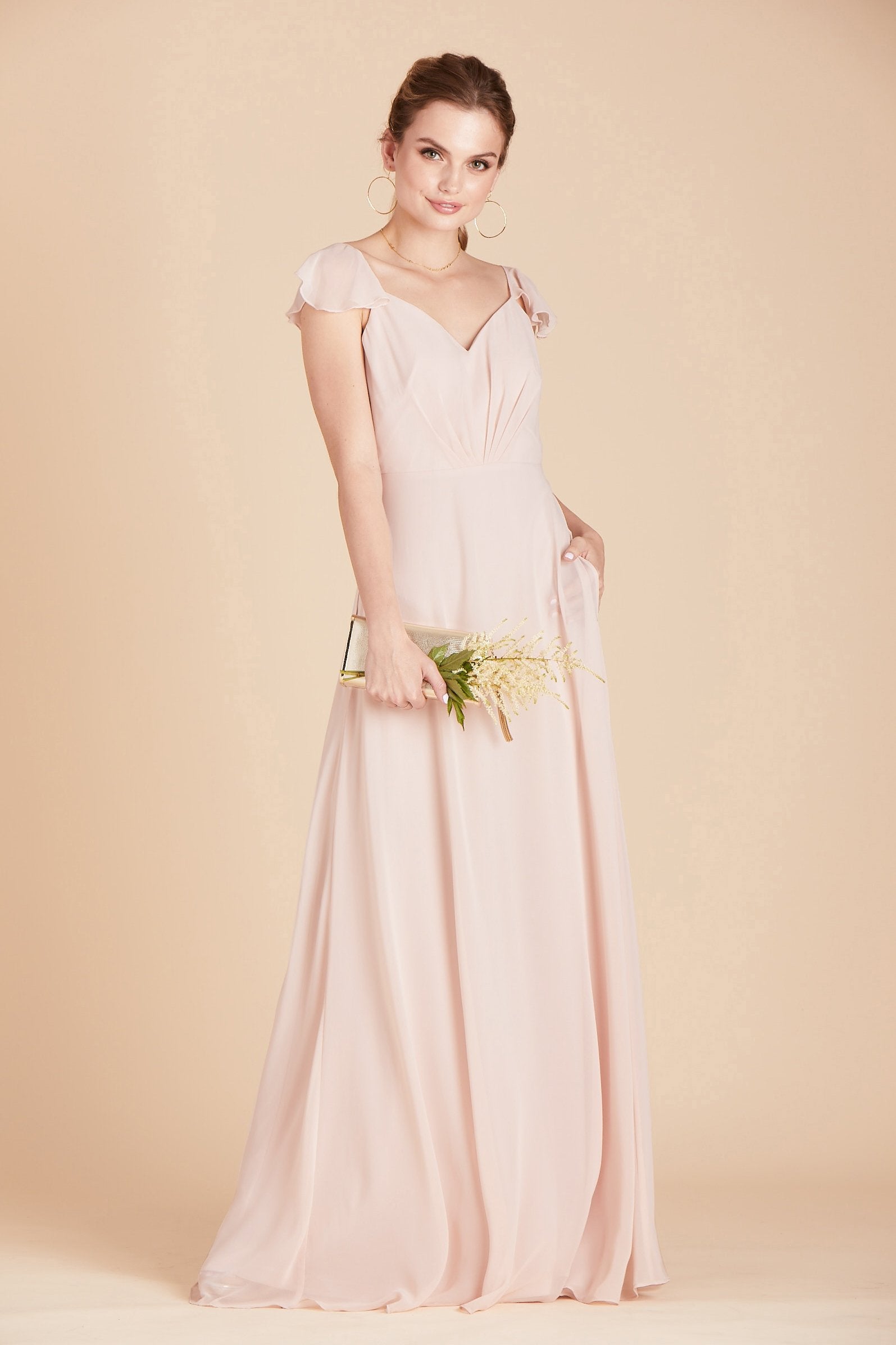 Kae bridesmaids dress in pale blush pink chiffon by Birdy Grey, front view with hand in pocket