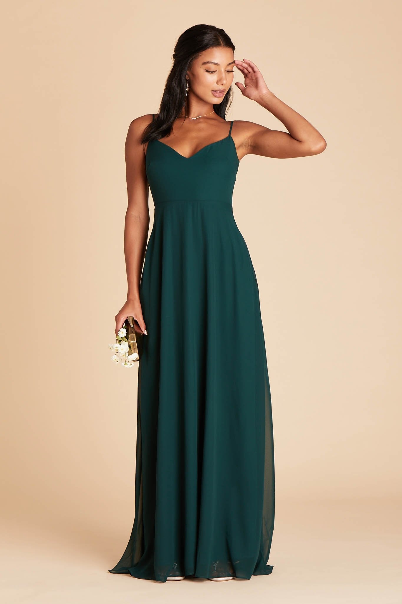 Front view of the floor-length Devin Convertible Bridesmaid Dress in emerald chiffon worn by a slender model with a medium skin tone. The flowing skirt has no slit, as this is an optional feature.