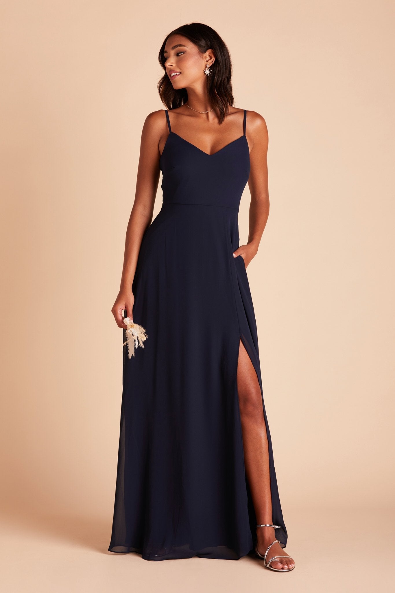 Devin convertible bridesmaid dress with slit in navy blue chiffon by Birdy Grey, front view with hand in pocket