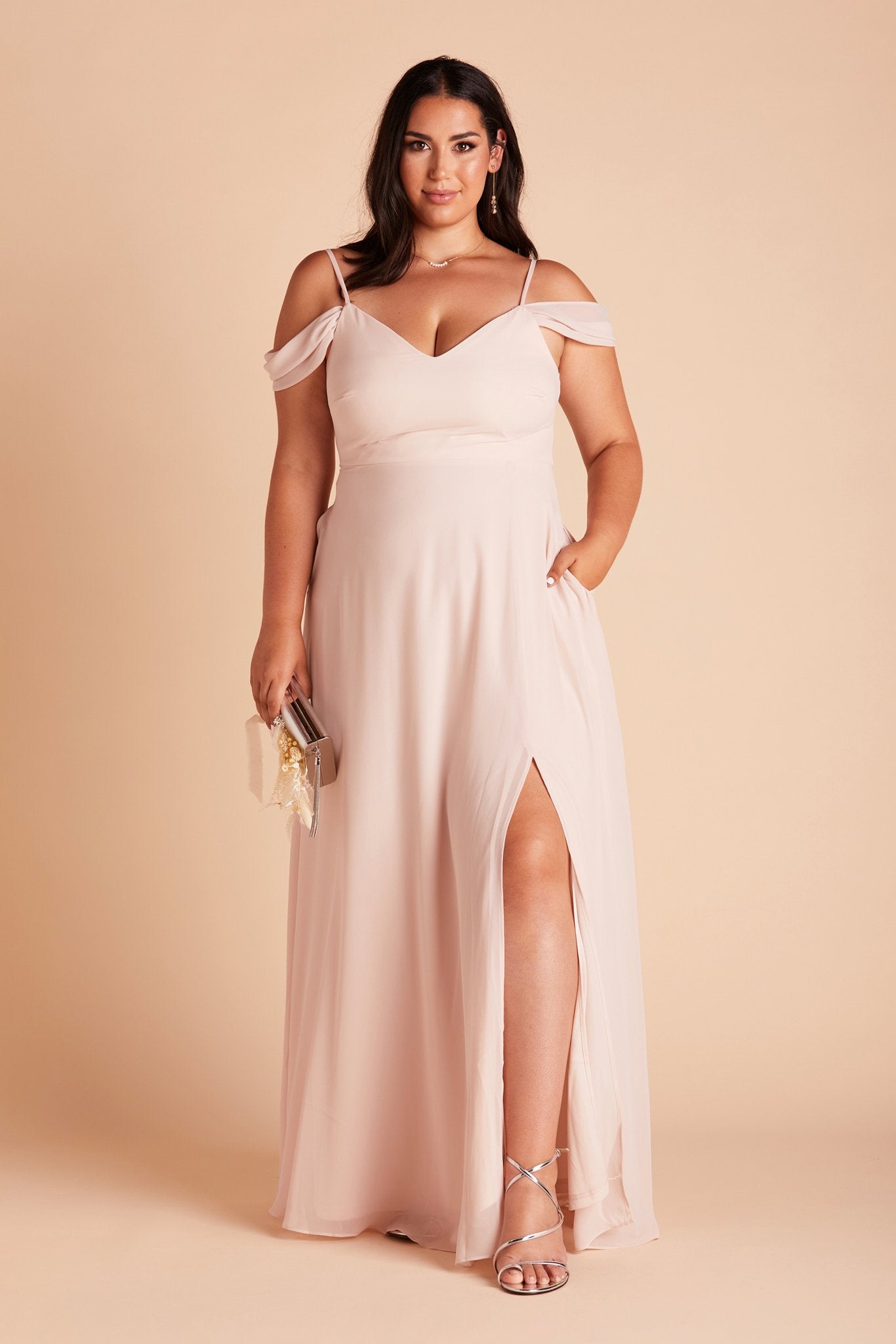 Devin convertible plus size bridesmaids dress with slit in pale blush chiffon by Birdy Grey, front view with hand in pocket