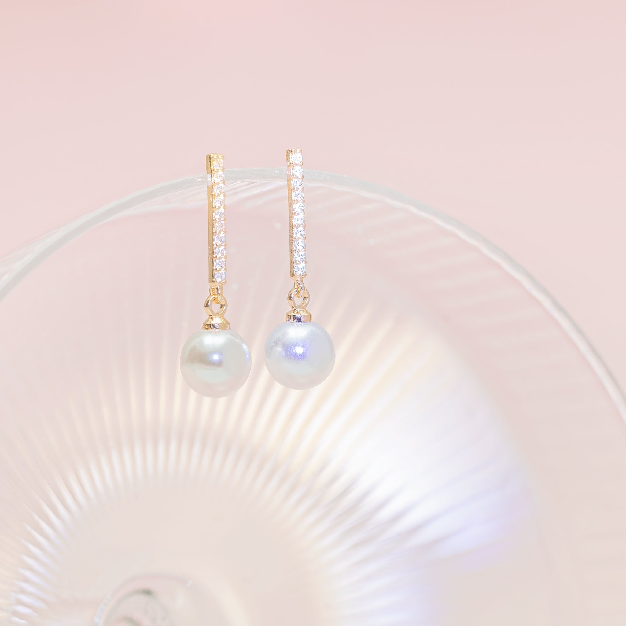 Dangling gracefully on a display, we see the Cincinnati Pearl Drop Earrings, cubic zirconia sparkling in the light as the plastic pearls gleam gently.