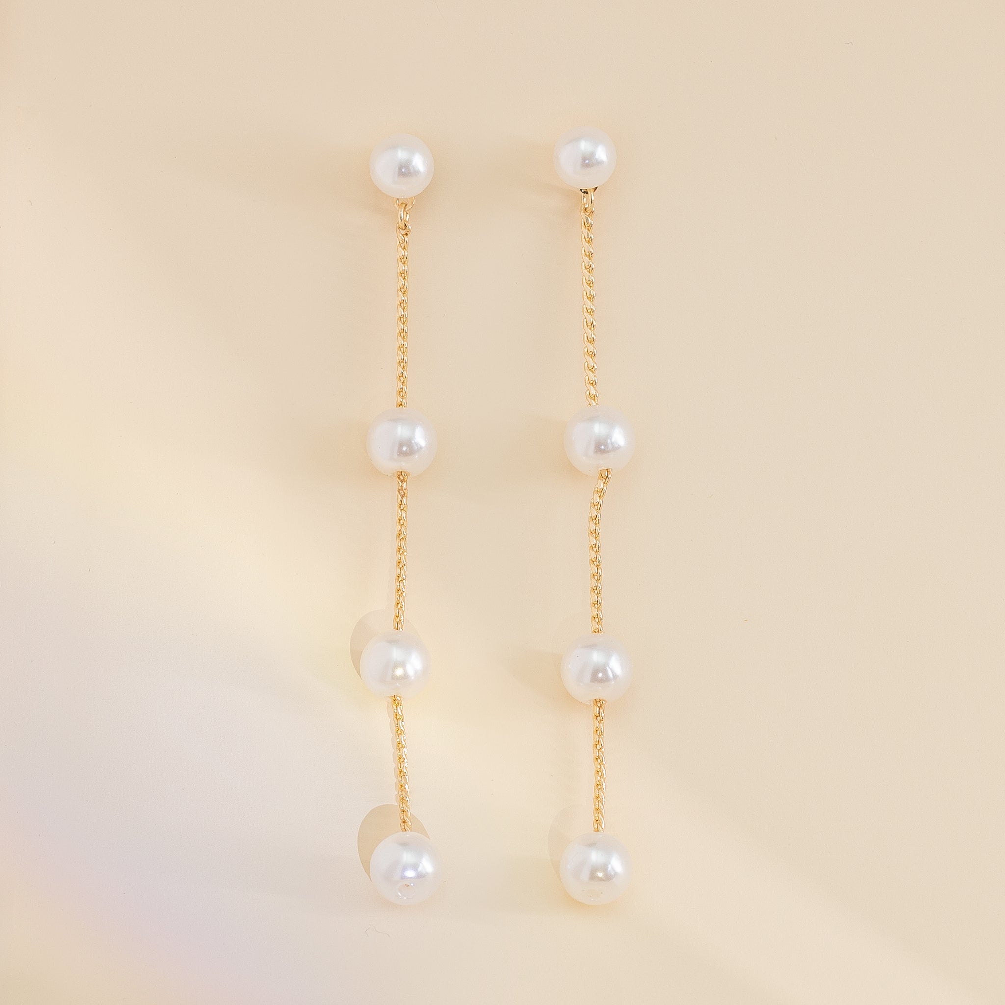 Closeup product view of the Lowell Pearl Earring Long showing the four pearls evenly spread over a gold chain.