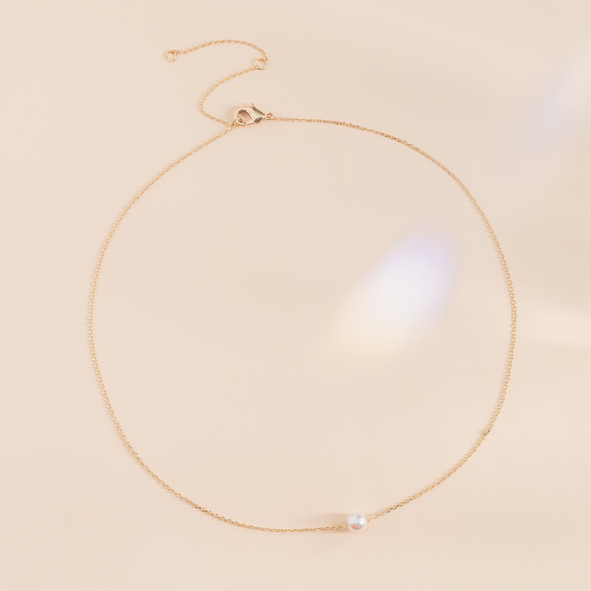 Flat view of the Santa Barbara Single Pearl Necklace shows a gold plated chain necklace with a single pearl. The necklace can be adjusted to three different lengths with an easy to open clasp.