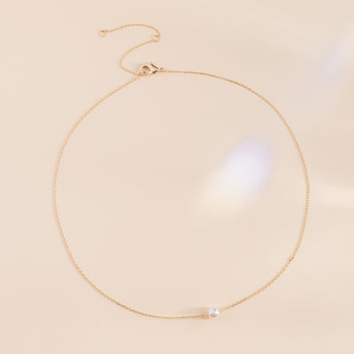 Flat view of the Santa Barbara Single Pearl Necklace shows a gold plated chain necklace with a single pearl. The necklace can be adjusted to three different lengths with an easy to open clasp.