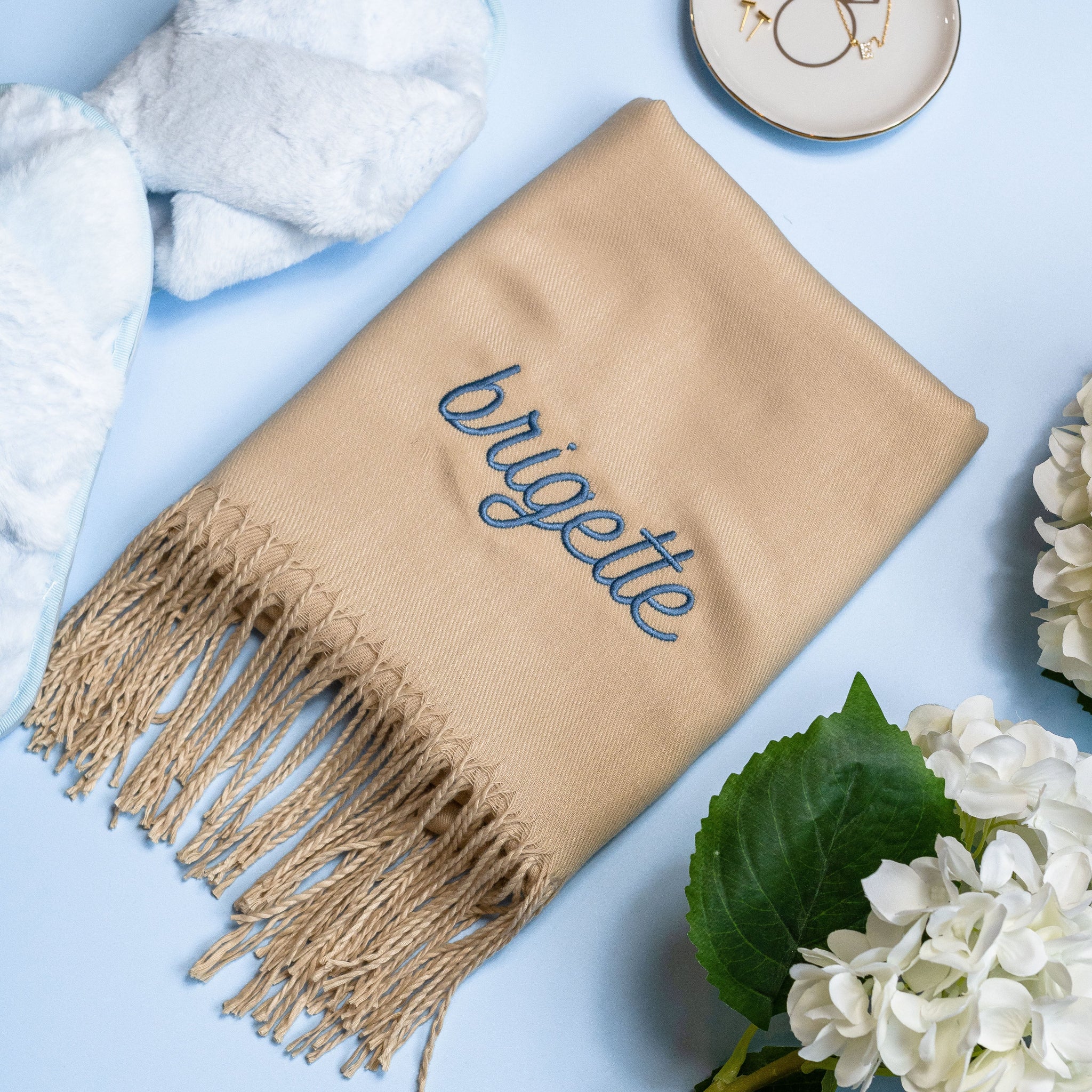 Flat closeup view of the Shawl with Fringe in beige folded in a rectangle with the name 