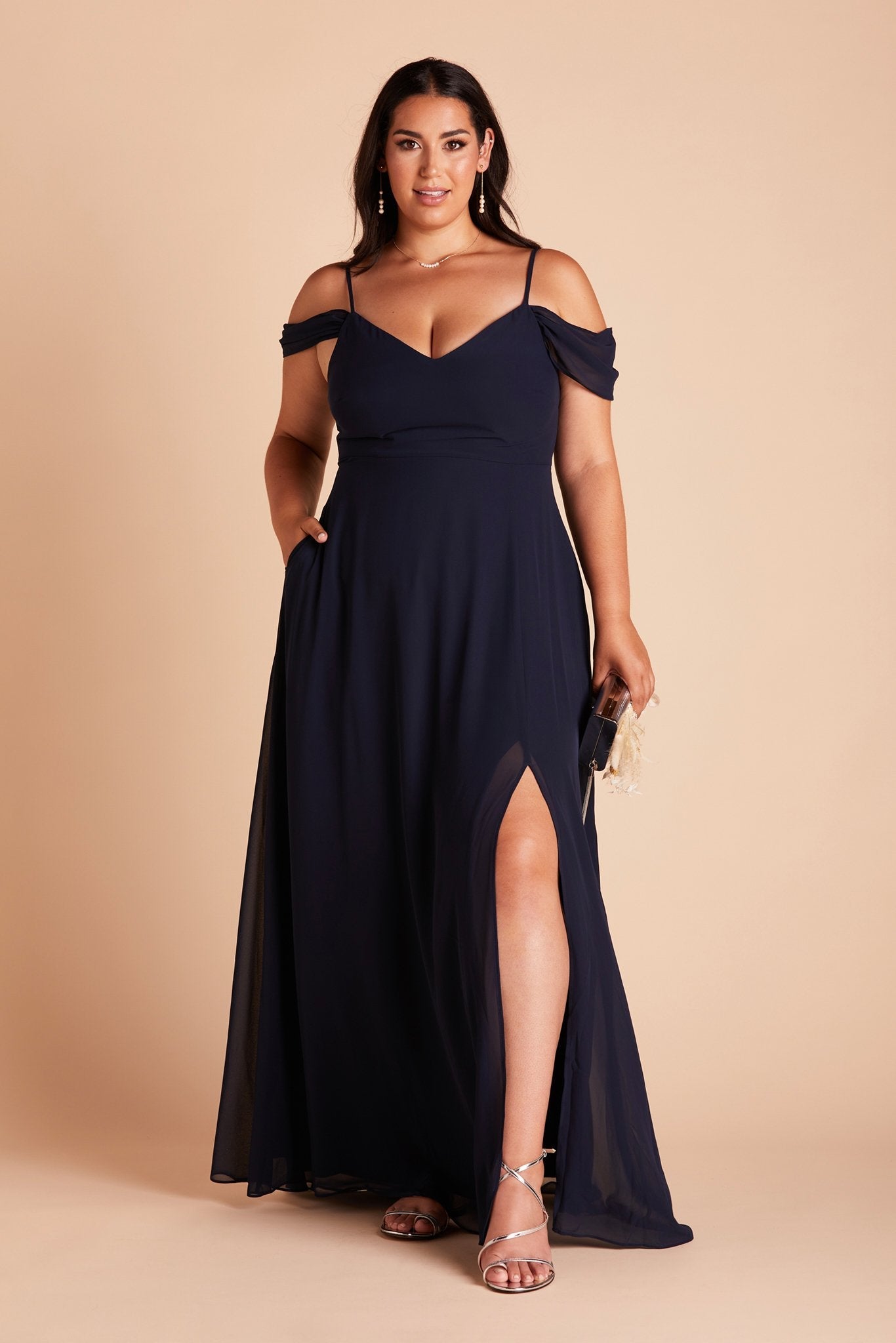 Devin convertible plus size bridesmaids dress with slit in navy blue chiffon by Birdy Grey, front view with hand in pocket