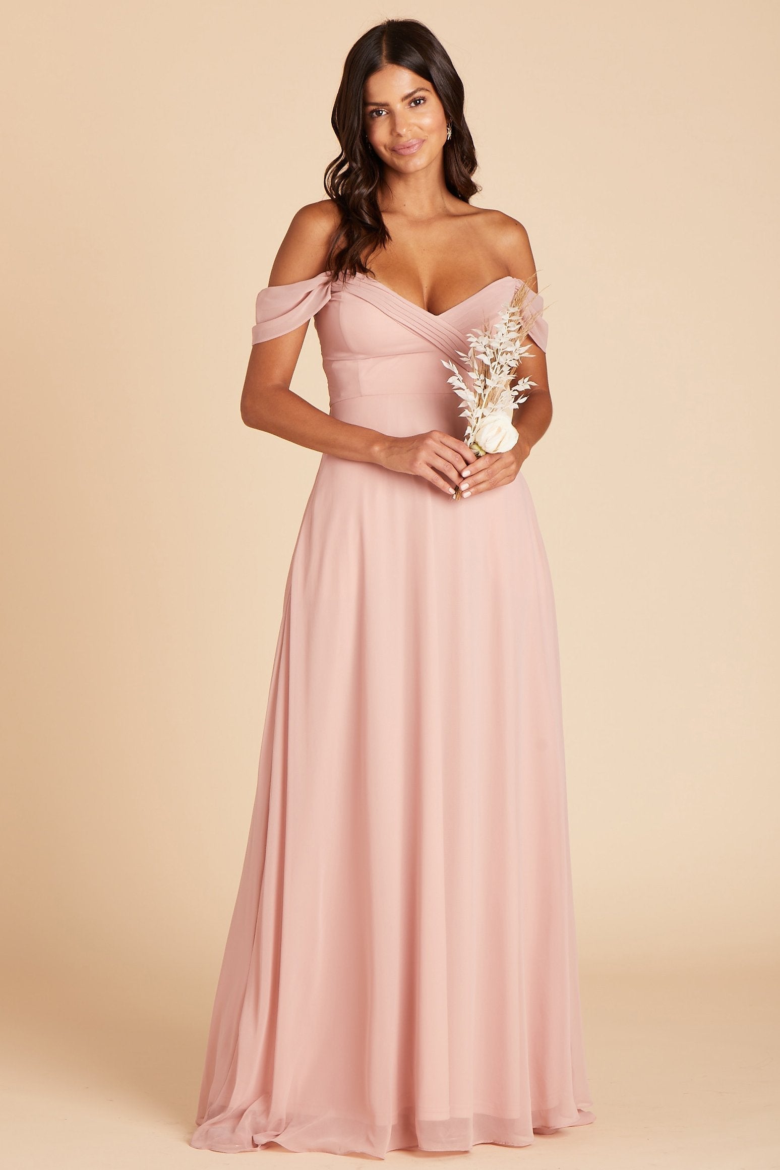 Front view of the Spence Convertible Dress in dusty rose chiffon shows a model holding a dried flower ivory bouquet. The fit of the bodice front shows a smooth fit with cleavage showing due to the built-in boning and bra cups. 