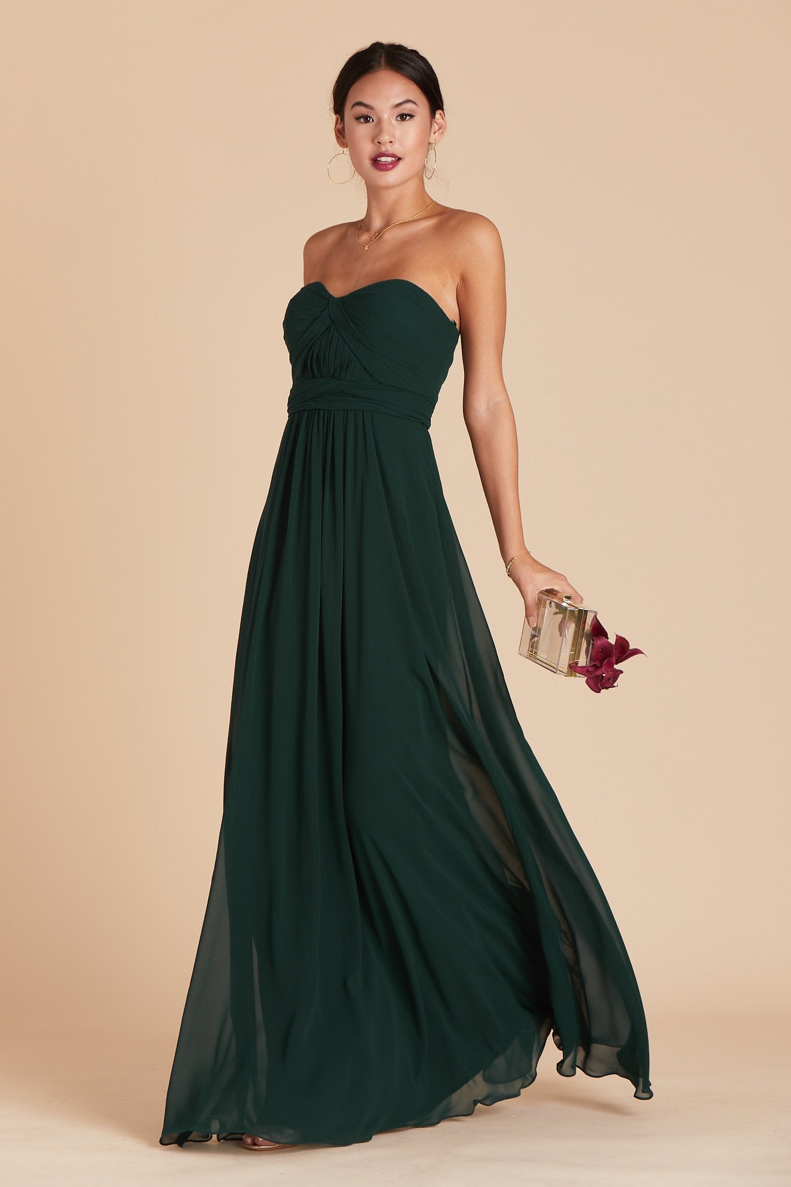 Front view of the floor-length Grace Convertible Dress in emerald chiffon features a fitted bust and waist with a flowing skirt that moves gracefully as the model steps forward.