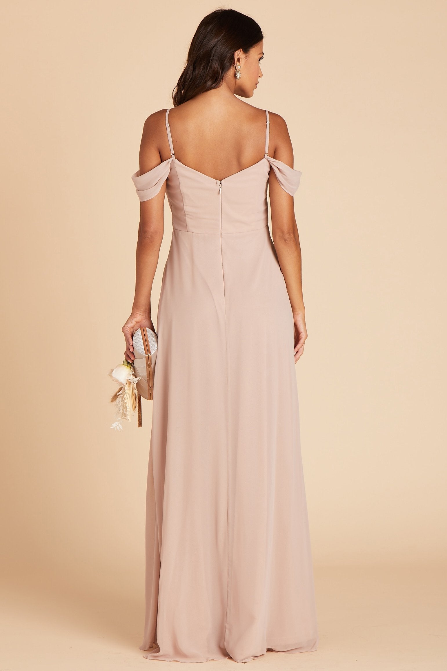 Back view of the Spence Convertible Dress in taupe chiffon shows the straps and the gentle flow of the shoulder sleeves, the hook and eye closure, and zipper in the center seam of the bodice and dress. The dress conforms to their body along the back and then flares slightly to the floor.