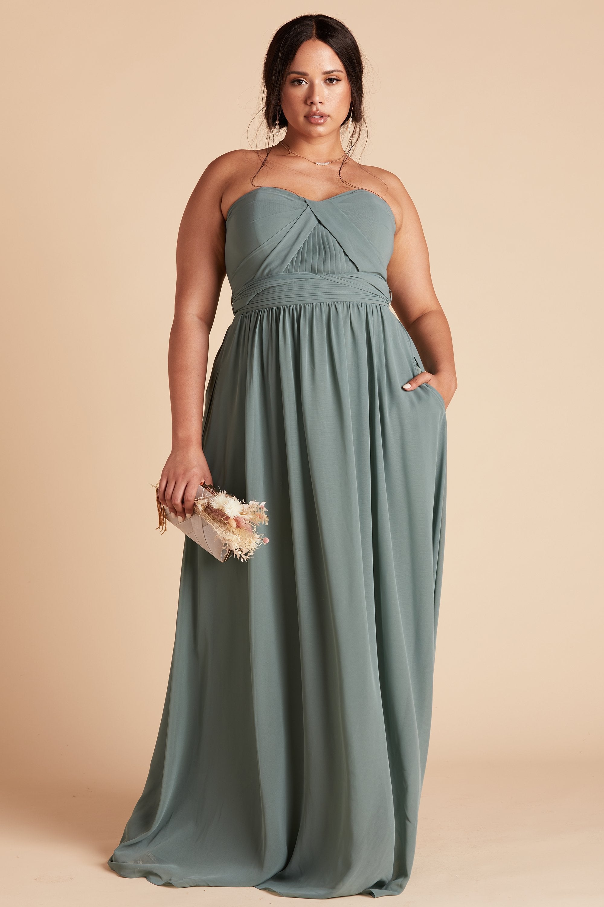 Front view of the Grace Convertible Plus Size Dress in sea glass chiffon as the model rests her left hand in the hidden side pocket.